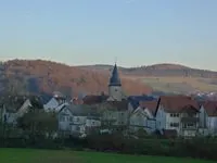 Blick auf Pfarrhausgarten und Kirchturm mit Blumenschmuck.